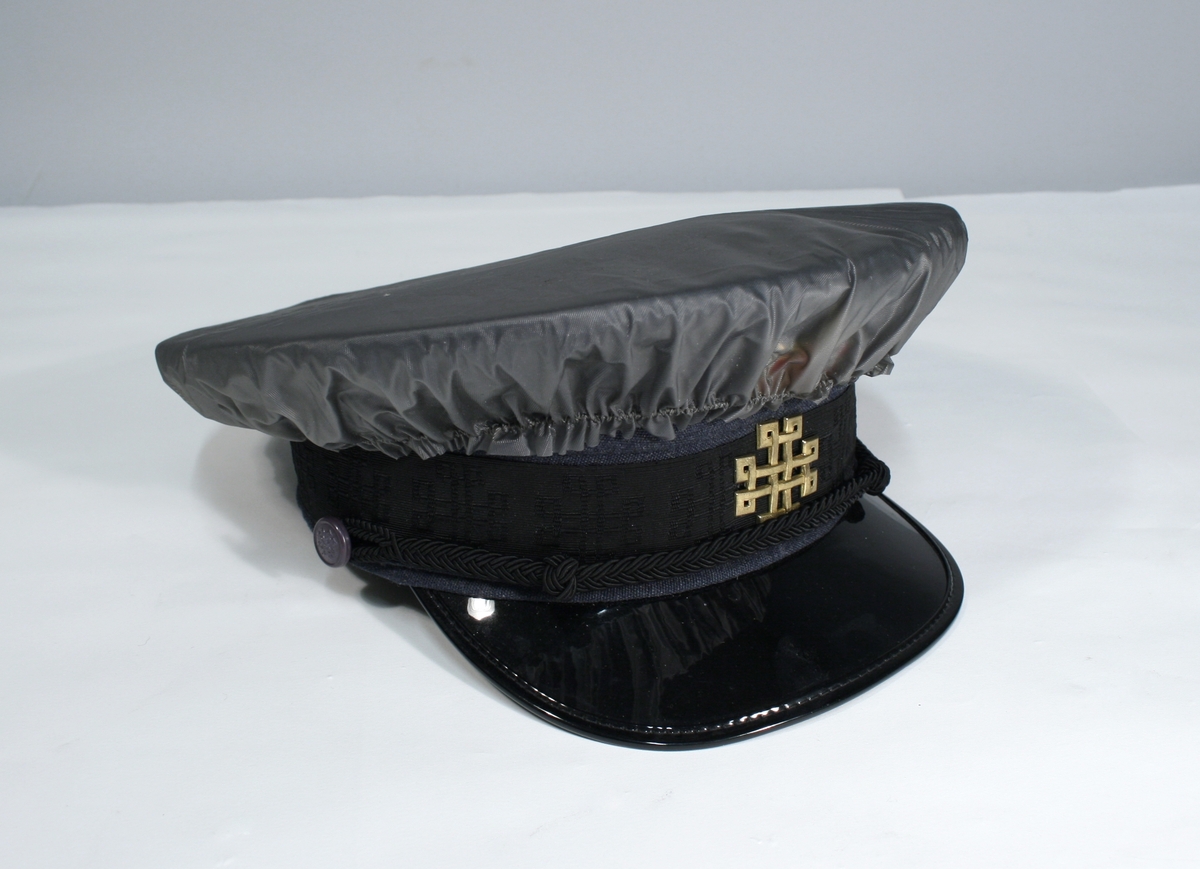 Lang grå uniformsfrakk, grå uniformsjakke, grå vinterlue (båtlue) med for i fuskepels, sort slips, grå uniformslue med blank sort skjerm og regntrekk, tre lyseblå uniformsskjorter. Uniformen har skulderklaffer med en gullstjerne, altså distinksjon for førstebetjent. Plasknapper med valknuten. Luene er forsynt med metallmerker i gull og rødt, den norske krone over valknuten som var symbolet for kriminalomsorgen i perioden 1964-2001.