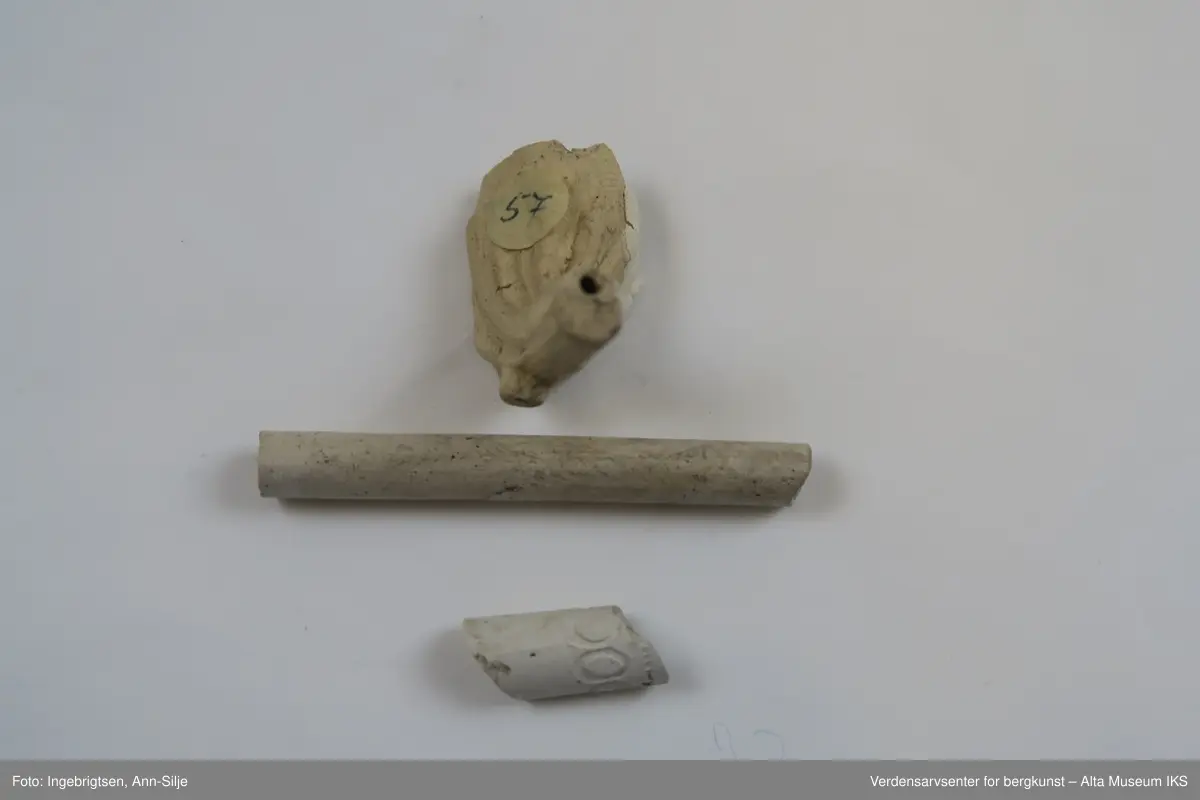 En samling fragmenter av krittpiper. Et av pipehodene er mer eller mindre hel, men med avbrukket pipehals. 

Fragmentene varierer i størrelse fra 1,5 cm til 5,7 cm i lengde og 0,5 cm til 2 cm i bredde.