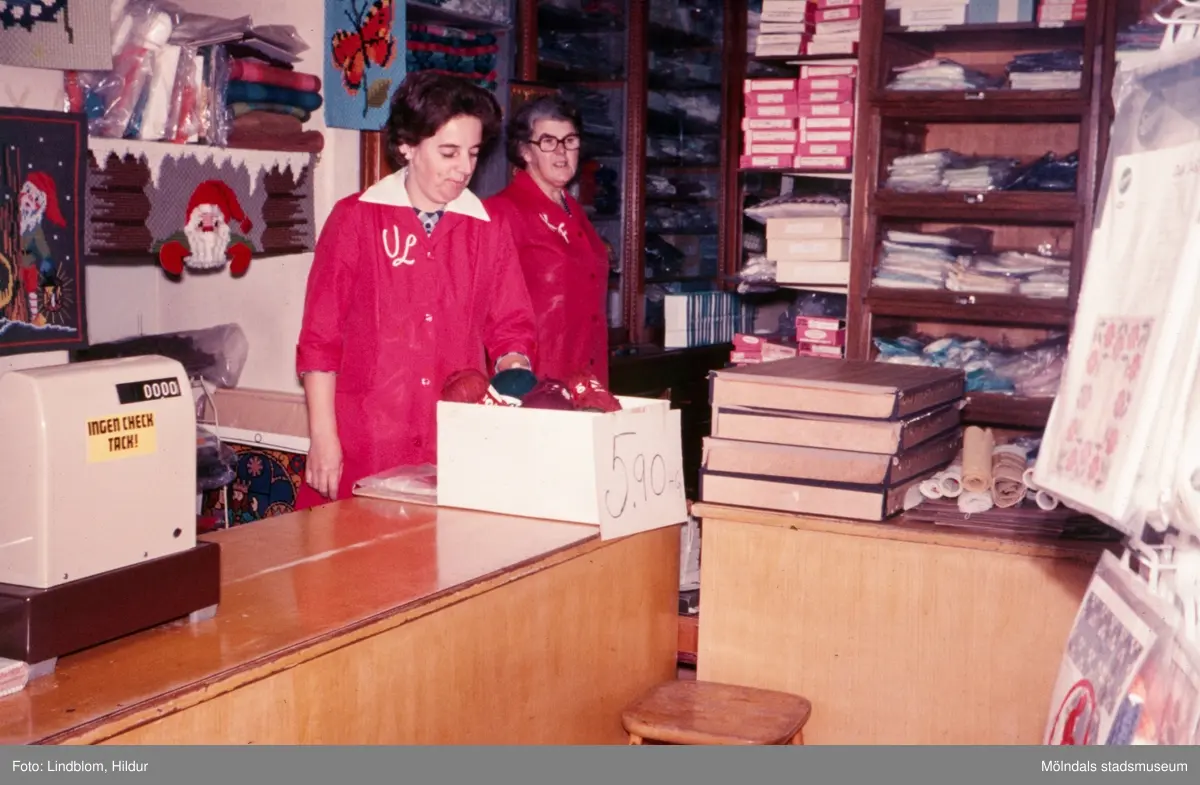 Från vänster Ulla Lindqvist och till höger Kajsa Forsell (född Andersson) som står vid kassan i "Kvarnbyns Trikåaffär" på Kvarnbygatan 37, 1970-tal. Affären var inriktad på bl.a. garner och handarbeten. Kajsa köpte affären ca 1950 från Inessa Skoglund och drev den tills huset revs på 70-talet. Ulla Lindqvist kom senare att arbeta i Rasmussons skoaffär.

För mer information om bilden se under tilläggsinformation.