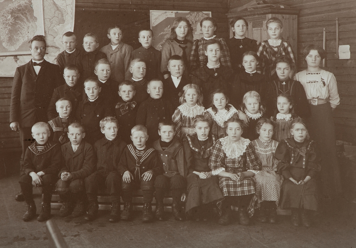 Tomter skole, Vallset, gruppe elever og lærere i klasserom.
1 rekke f.v. ukjent, Sigurd Søgård, f. 20.10.1899, Per Sveen f. 09.11.1900, ukjent, ukjent, ukjent, Karen Lie g. Finberg f.03.02.1900, ukjent, ukjent. 2. rekke f.v. Nils Tøstiengen f. 28.11.1904 ( ikke elev), Anton Tøstiengen f. 17.07.1900, Anders Refsahl (?) f. 31.10.1901, Gunnar Lie f. 14.12.1901, ukjent, ukjent, ukjent, ukjent. 3 rekke f.v. ukjent, ukjent, ukjent, ukjent, ukjent, ukjent, Elida Tøstiengen g. Solvang  f. 27.06.1897, ukjent, ukjent. 4. rekke f.v.  ukjent, ukjent, ukjent, ukjent, ukjent, Anna Lie g. Bjerkan, f. 05.06.1896. Lærer og klokker Anders Harildstad f. 12.09.1875, lærer ved Tomter skole 1897-1935, lærerinne ukjent.