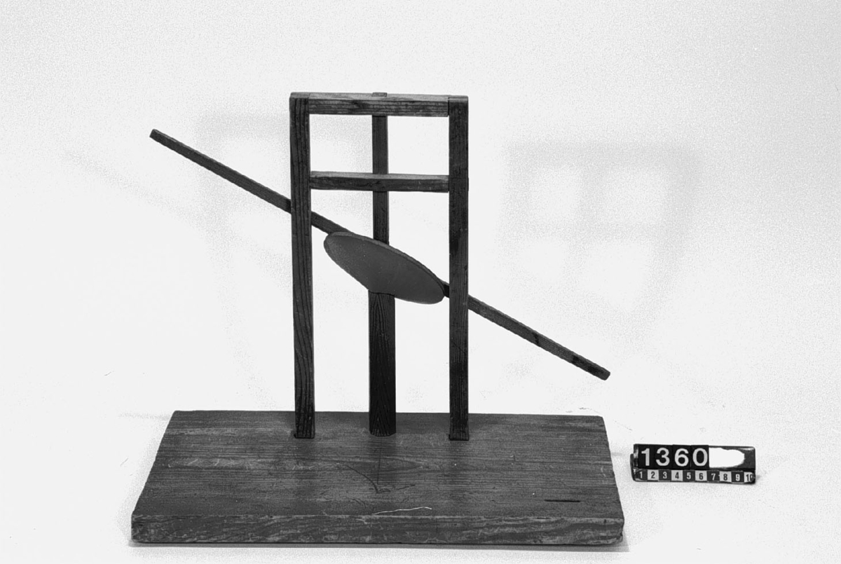 Modell ur Polhems mekaniska alfabet. Text på föremålet: "LXIV". Vid rotation av den lodräta axeln erhålles med hjälp av den vinkelställda skivan en vickande rörelse hos armen.