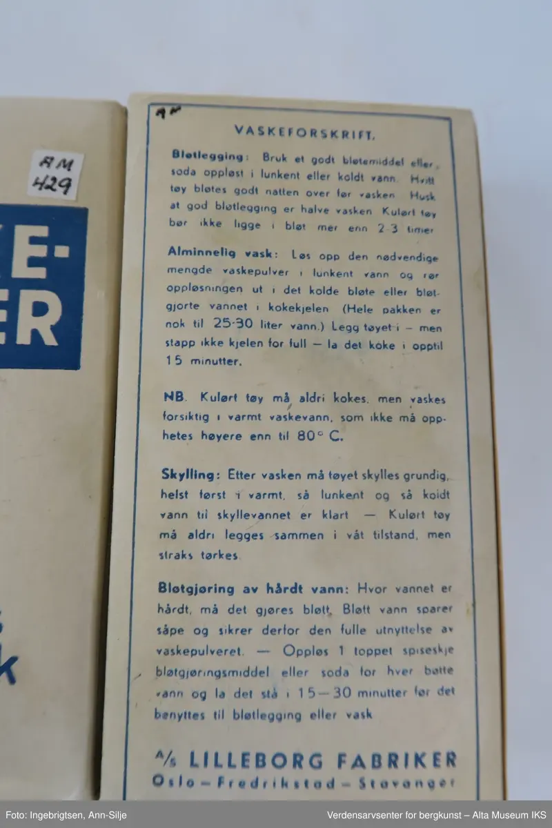 Hvit rektangulær pakke med pulver. Øverst på pakkens forside er det et blått felt med hvit skrift. Ellers er det tekst i blått skrevet på alle sidene på pakken.