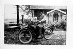 Fotografi från Södra Billinge, Kils socken. Året är 1920. Hugo Hammarlund har inköpt en motorcykel  Excelsior Chicago, 1000 cc, 1920 års modell för 3000:-.
I sidovagnen sitter brodern Gustaf med sin dotter Ingrid, född år 1919. I bakgrunden deras föräldrahem i Södra Billinge by. Observera den vackra snickarglädjen på verandan. Motorcykeln är en Excelsior på 7-9 hk som registrerades den 12: augusti 1920 och ägdes av lantbrukare Hugo Hammarlund, Södra Billinge, Närkes Kil.