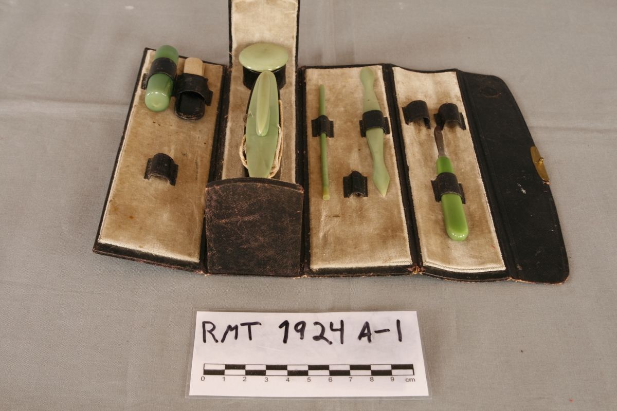 Manikyrsett med opprinnelig tolv deler i tillegg til etuiet. Etuiet har en kjerne av papp, dekket av kunstig skinn. Trykklås av metall. Etuiet kan brettes helt ut, endeveggene er stive. Innsiden har dekke av lys brungrønn fløyel, hver side har holder til tre deler av manikyrsettet. Jadegrønn finish på de ulike manikyrdelene.