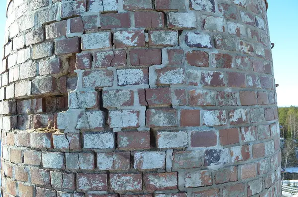 Restaurering av ei gammal stor mursteinspipe. Tydelige skader og mangler på murstein.