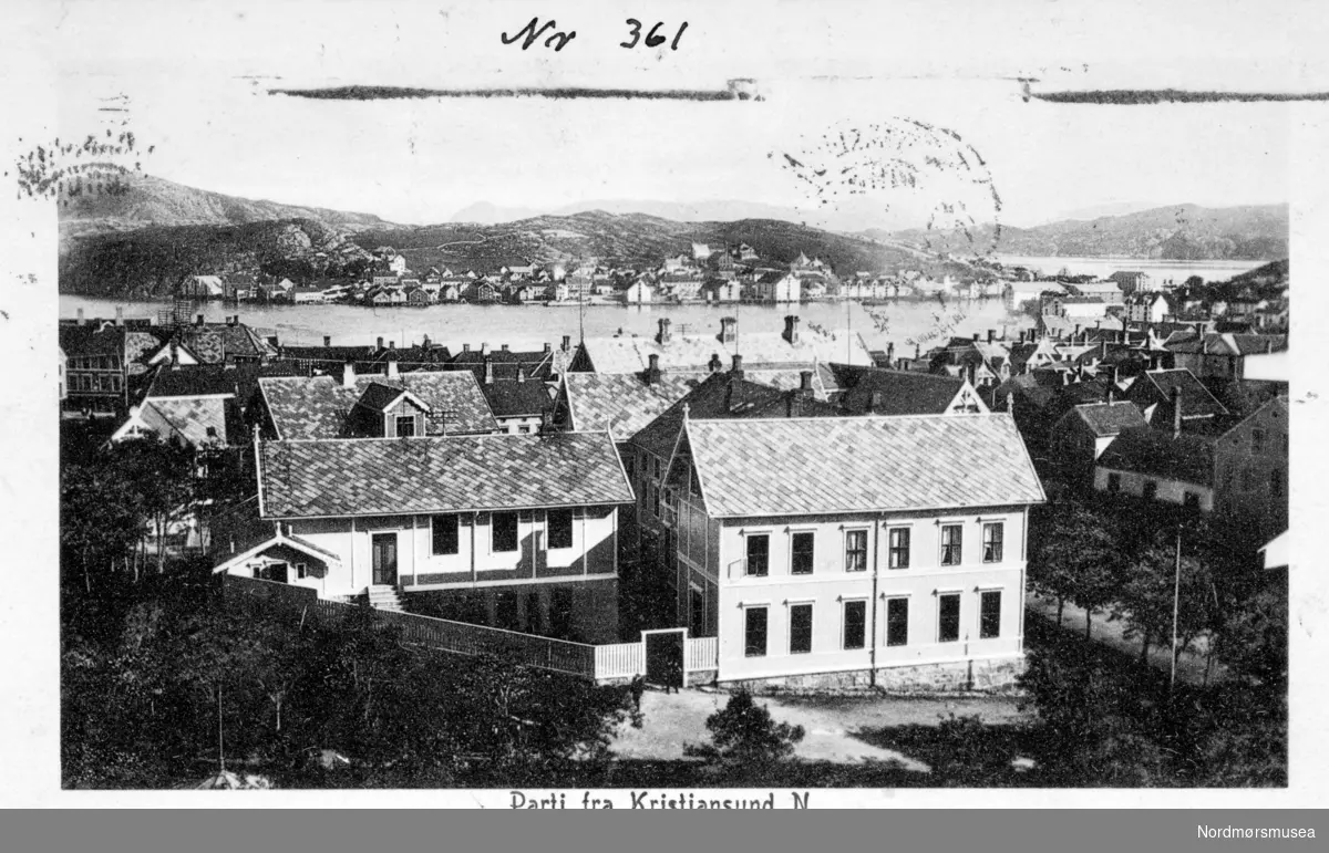 ";Parti fra Kristiansund N."; Postkort med motiv fra den Høgre Skole  i Skolegata på Kirkelandet, vistnok fotografert fra kirketårnet omkring 1910. Skolen ble bygd omkring 1870, og en ser den gamle gymnastikksalen til venstre med W.C. Gymnastikksalen ble i 1921 solgt til Frei og er nå bedehus ved Frei kirke. Fotograf er trolig Johan K. Engvig. Reg: EFR
