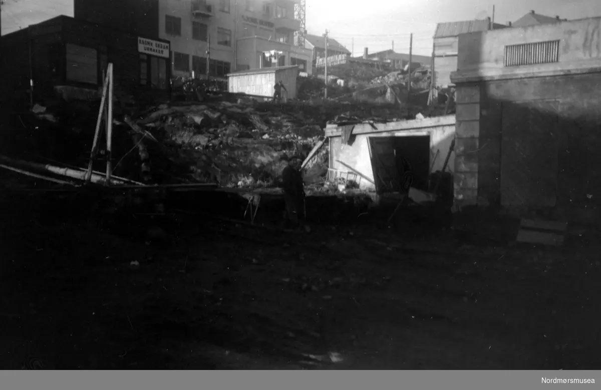 Grunnarbeidet til det nye rådhuset i Kristiansund er i gang, nord for Loennechengården. Bildet er fotografert fra Sør-øst, over fra Fisketorget og Kaibakken. Rådhuset ble ferdig oppført i 1953, og arkitektene bak bygget var Molle og Per Cappelen, som vant konkuransen om oppføringen av rådhuset i 1947, med omkamp-konkuranse i 1948. Bygget er reist på armert betong i to volumer: En kontorfløy og en bystyresal, med det hele på en sokkeletasje. Nordmøre Museum: se flere bilder i samme serie