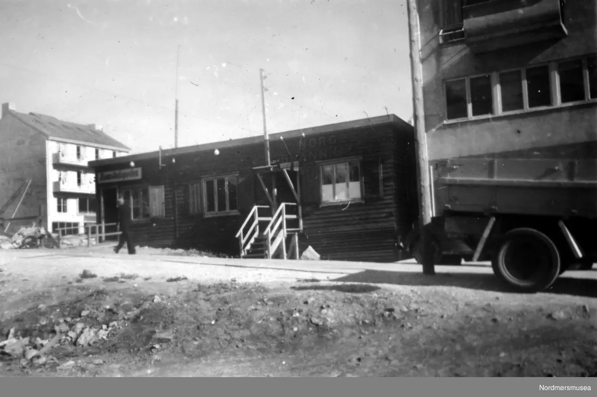 På bildet ser vi brakka til avisa Romsdalsposten i Skolegata, samt Bolgens brakke. Se også bilde KMb-1949-000-1096. Fra Nordmøre Museums fotosamlinger.
