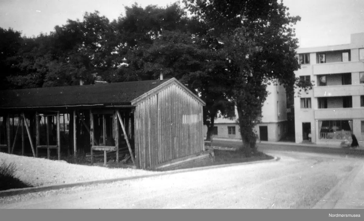 Knoblochs rammeverksteds brakke ved Roligheten (ovenfor den seinedre Kirkelandets kirke 1963), i Peter Rosentræders gate. Nå rives den, sammen med de andre brakkene i Roligheden. Det ble lekeplass her. I bakgrunnen ser vi Langveien og Damehjemmet/seinere Frimurerlosjen. Bildet er datert oktober 1953. Nordmøre Museum