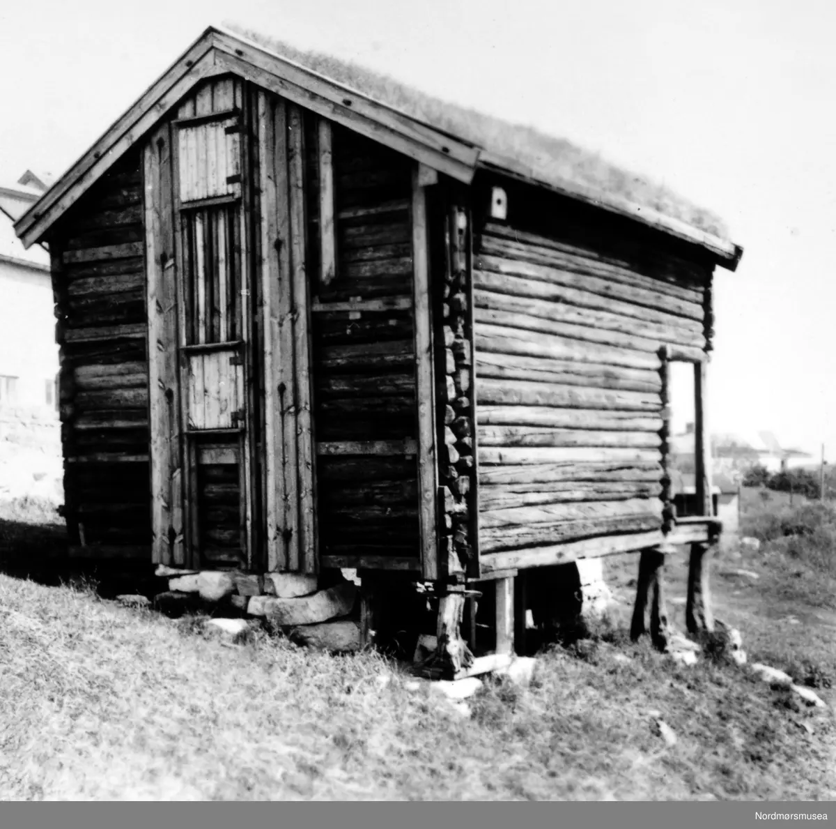 Flyumstabburet, Nordmøre museum, med borkledningen mot vest, delvis revet før flytting fra Clausenenga. Datering av bildet er 26. juni 1959. Fra Nordmøre Museums fotosamlinger.
