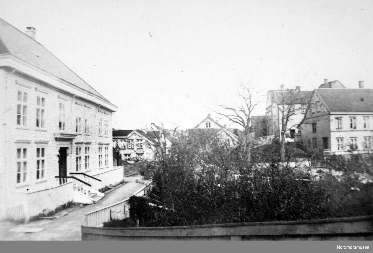 "Staldbakken". Foto med deler av bebyggelsen i Vågen på Kirkelandet i Kristiansund, hvor vi blant annet ser Christiegården/Håndverkerforeningen til venstre på bildet.  Bildet er fra fotoalbumet "Christiansund i Fotografeir". Bildet er trolig fra 1883 etter informasjon fra Willhelm Lund samlingen. merk trappa, verandaen og Allanhagen (der Helsehuset er på 2009). Fra Nordmøre Museums fotosamlinger.
