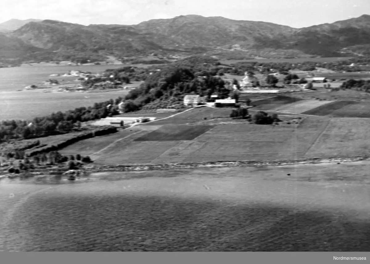 Flyfoto over Frei med Frei kirke og nær bebyggelse. Nerfrei gård, Rastarkalv. Bilde fra fotoinnsamlinga i Frei 1978-79. Innsamla av Freielever på Nordlandet ungdomsskole og registrert av Randi Røe. Fra Nordmøre Museum sin fotosamling.