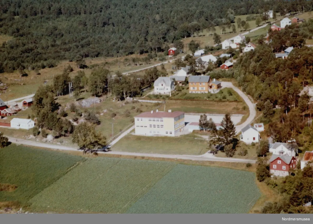 Flyfoto fra Tingvollvågen folkeskole på Tingvoll. Dette bygget er per oktober 1992 kommunehuset. Det er også blitt bygd helsestasjon på tomten.Nedenfor ligger i dag (1992) Tingvoll Sparebank. Veien øverst i bildet leder opp mot Vågbø. Bildet er datert 30. juli 1963, og fotograf er Widerøe's Flyveselskap a/s. Fra Nordmøre Museums fotosamlinger. /Reg:EFR2013/



