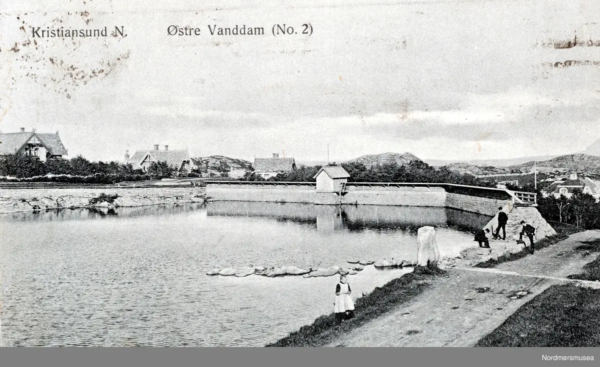 Postkort: "Kristiansund N. Østre Vanddam (Nr. 2). Foto fra Vanndamman i byparken. Her sees dam nr. 2 av totalt 4 dammer som utgjør Vanndamman på Kirkelandet. Oppbyggingen av et regulært vannverk for Kristiansund skjedde da brann- og veiinspektør Peder Rosentræder i slutten av 1850- årene planla, og oppførte en dam som lå like ovenfor Roligheten. Dammen fikk navnet Svanedammen på folkemunne. Fra Nordmøre Museum sin fotosamling. EFR2015