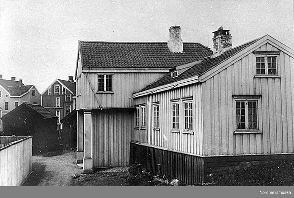 Katalog over bilder av eldre gateparti, bygninger og bygningsdetaljer i Kristiansund. Bildene er bekostet av Det Kulturhistoriske Lag (DKL)og med bidrag av Kristiansund Sparebank og fru Caroline Knudtzon. Ført i protokoll av overlærer Wilhelm Lund. Foto hovedsakelig utført av fotograf Ole Olsen Ranheimsæter dersom ikke noe annet er anført. Tegninger utført av billedhugger J. Johnsen og Ole Ranheimsæter. DKL - er en forløper for Nordmøre Historielag, i tett samarbeid med Kristiansunds museum. Nr. 60 H. M. Neeraas meddeler om dette parti: "Fotografiet gjengir "Schaanninggaarden", saakaldt efter den daværende eier fhv. prost Schaanning. Gaarden sees fra baksiden. Længst til venstre sees det til gaarden hørende stabbur. Bygningen laa ved torvet, Kirkelandet, pa det nuværende Grand Hotels tomt." H. M. Neeraas meddeler at ovenævnte oplysninger er bygget paa hans egen erindring. Billedet er kopi efter ældre fotografi, som ifølge O. Ranheimsæter er tat av ham, sansynligvis i sluten av 1880- årene. Fra Nordmøre Museum sin fotosamling.

Jens Christian Folkman Schaanning (1804-1886), sokneprest i Kristiansund 1826-74, prost i Nordmøre 1858-70 og politiker. Bystyret 1839-71, ordfører 1839-42,47,49-50,52-53. Stortingsrepr 1848,51,60. Gate oppkalt i Vågen.
