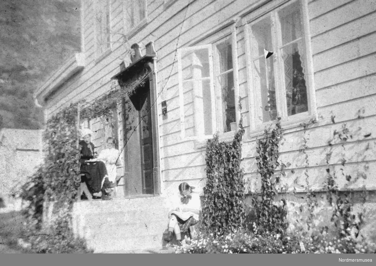 Foto fra en ukjent hus (sykehjem?), hvor vi ser tre kvinner sittende ute på og ved trappen.
Ukjent hvor og
hvem
Datering er også ukjent, men trolig omkring 1918 til 1919. Se andre bilder av samme hus på reg. nr. KMb-1983-024.0107 og KMb-1983-024.0108. Bildet ble gitt til Nordmøre museum av Nelly Rødsand 5. september 1983. Fotoalbumet består av bilder med reg. nr. KMb-1983-024.0049 til KMb-1983-024.0223. Flere bilder fra andre album er å finne på samlingsnummer KMb-1983-024. Fra Nordmøre museums fotosamlinger.
