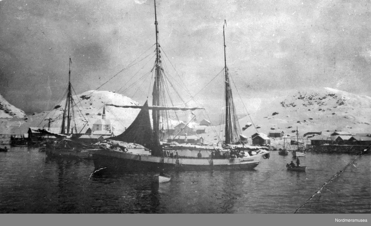 Moskenesvågen, Moskenes kommune i Lofoten. Moskenes kirke. 
(Info fra Sigbjørn Lauritzen - 30.01.2017.)  fiskefartøy, fjord nær kai . Det er sannsynligvis
 galeasen "Ingeborg" vi ser i forgrunnen. Datering er omkring 1900-1030. Fra Nordmøre museums fotosamlinger-