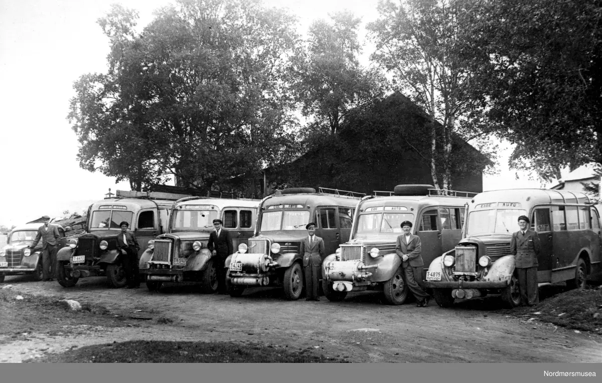Eide Autos 5 busser, inkl T-4875, T-4245 og T-4410 ved Kvernes stavkirke? Stevne? Sjåfører. Generatorer, dvs under krigen ca 1943? Fra Nordmøre Museum sin fotosamling.