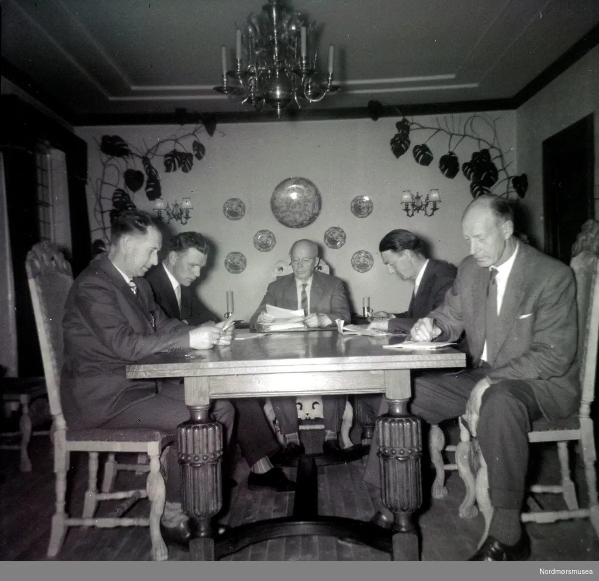 Foto muligens fra et arbeidsmøte? Her ser vi en gruppe menn sittende rundt et bord. Fotograf er ukjent, men kan være fra Fasting familien eller deres omgangskrets. Fotoserie. Fotografier gitt til Nordmøre Museum fra Kate og Kristian Fastings arvinger per 1986. Fra Nordmøre Museums fotosamlinger. 