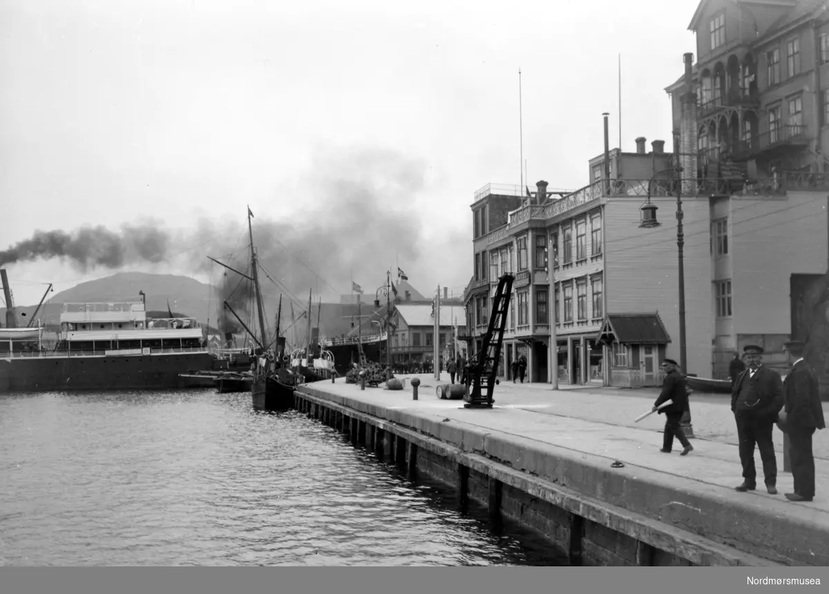 Foto fra Vågeveien med Vågekaia i front. I bakgrunnen ser vi en større dampbåt liggende fortøyd ved Kirkelandet Allmenning/Piren. Ellers så ser vi
Farstadhuset
til høyre oppe på høyden og beliggende i Byfogd Aass gate.
 Gullagården ligger nede ved på kainivå. Datering er omkring 1920-1939. Fra Nordmøre Museums fotosamlinger.
