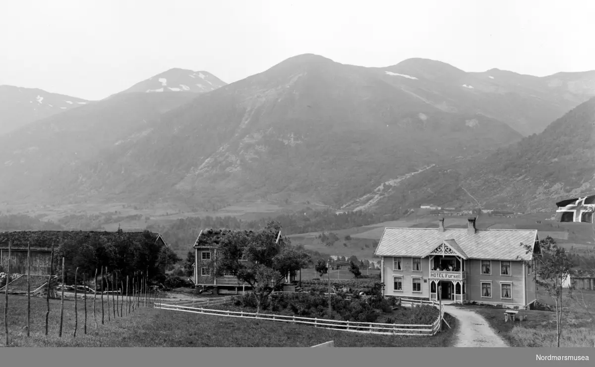 Foto av Hotell Furset, med låve og uthus, serie.  Her ser vi også det ruvende fjellet i bakgrunnen. Fotograf er trolig Georg Sverdrup og datering er sannsynligvis fra perioden 1930 til 1939. Fra Nordmøre Museums fotosamlinger.