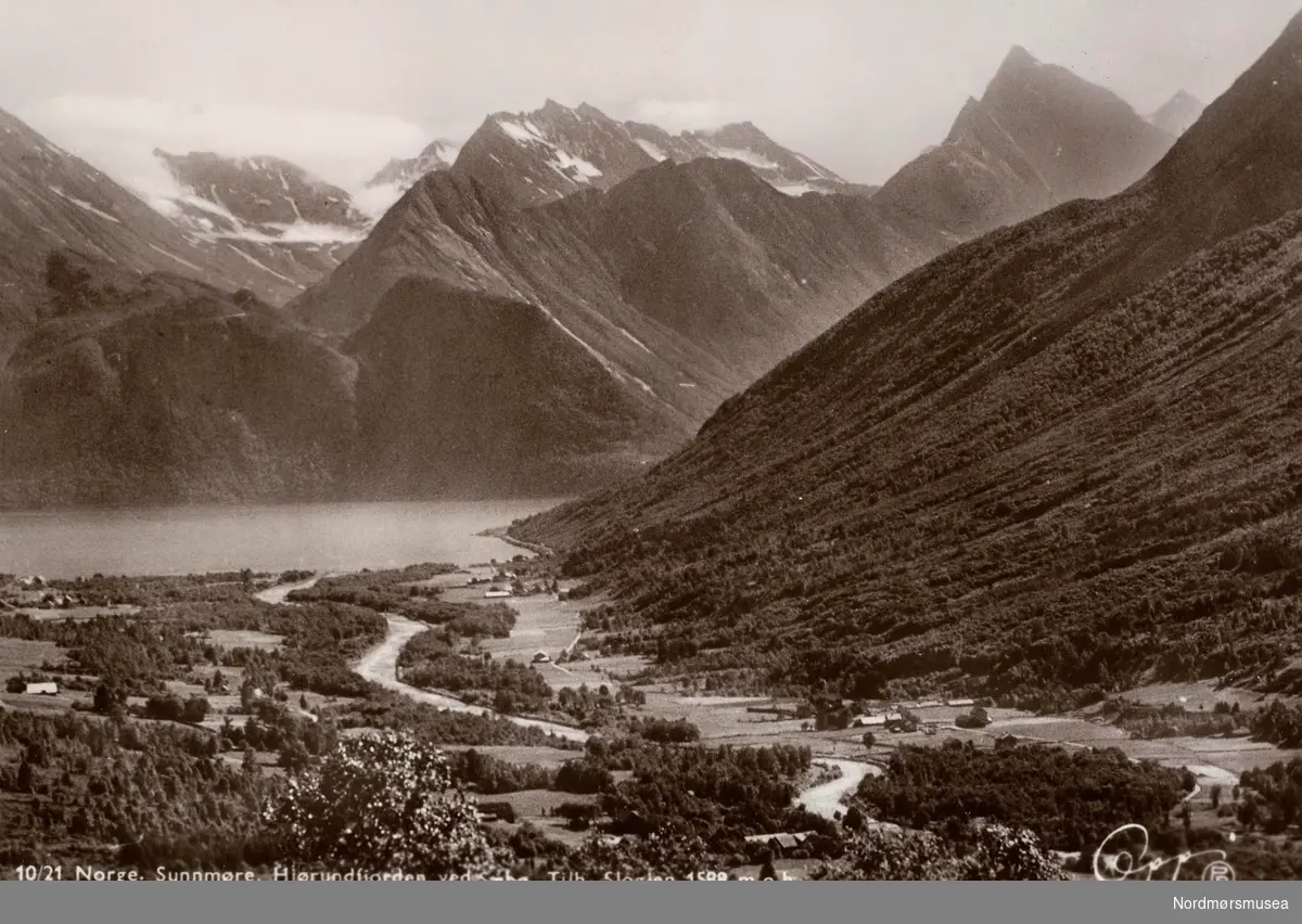 Postkort ";10/21"; med motiv fra Hjørundfjorden ved Sæbø, med Slogjen (Slogen) som rager 1588 meter over havet, i Geiranger, Ørsta kommune. Utgitt av Eberh. B. Oppi A/S. Fra Nordmøre Museums fotosamlinger. Reg: EFR

