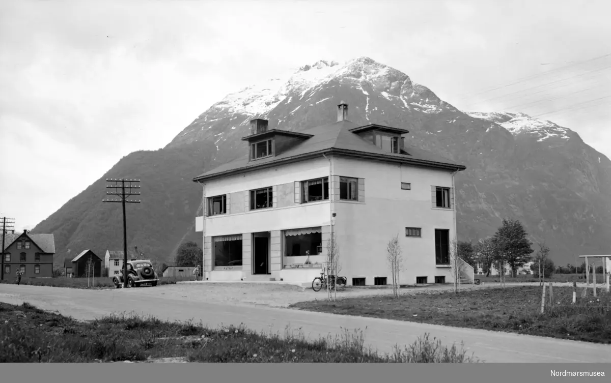 Foto fra handelshuset P. Støle, muligens i Surnadal kommune? Se også reg. nr. KMb-1987-005.1414 for et annet bilde av samme bygget. Fra Nordmøre museums fotosamlinger. - Dette handelshuset, og fjellet i bakgrunnen er ikkje frå Surnadal. (Tilleggsinfo: Magne Holten.)



