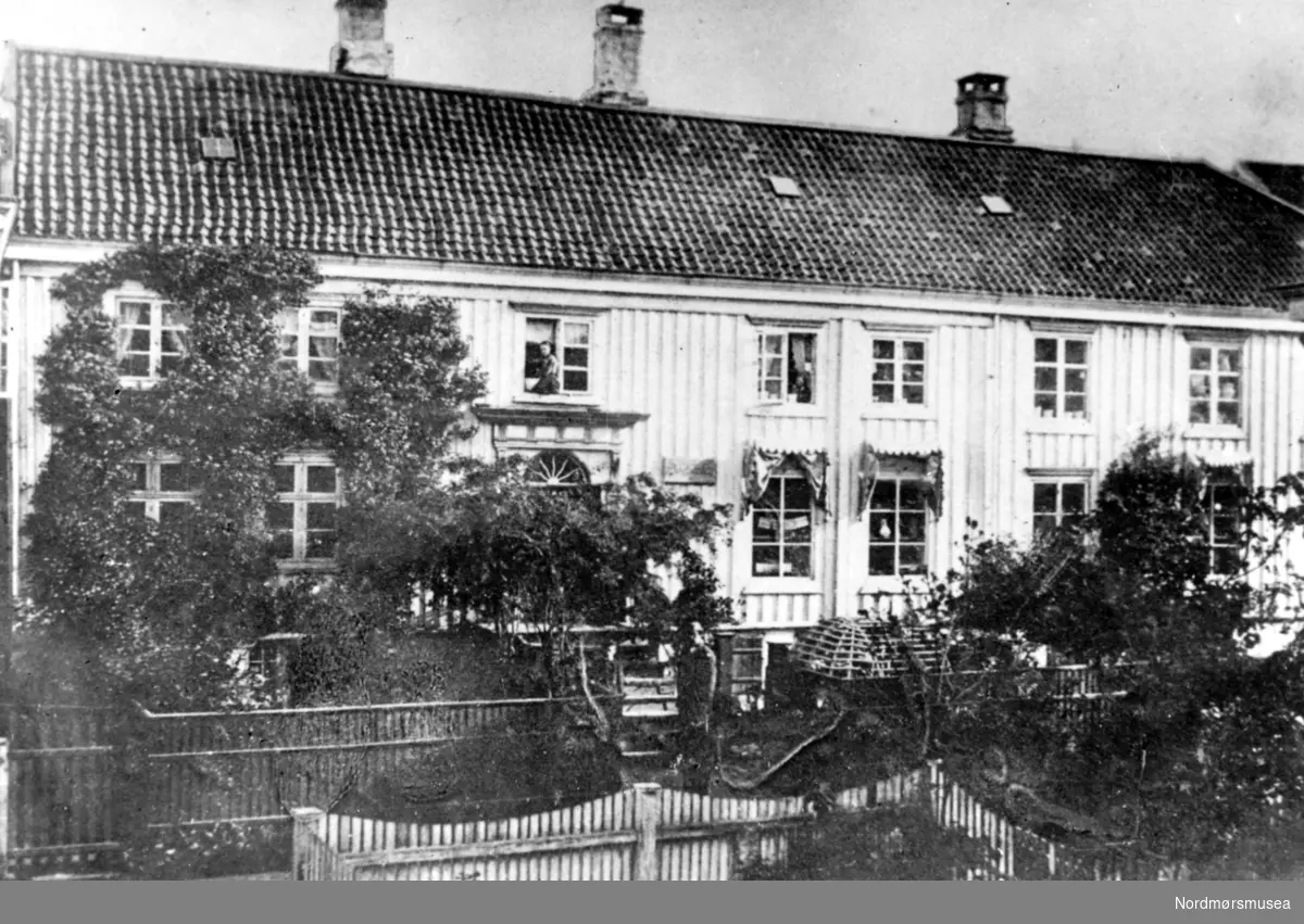 Foto fra Neraasgården i Storgata på Kirkelandet i Kristiansund, senere Bolgens auksjonslokale. Bildet er trolig fra tiden rundt 1890 til 1910. Gården brente ned til grunnen under bombingen av byen i april 1940. Fra Nordmøre Museums fotosamlinger.
