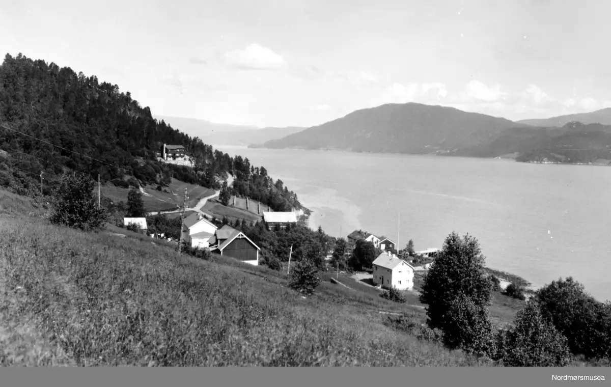Direktørboligen til Rausand gruver, øverst i bildet, ble bygd i 1939. Info: Siw Nilsen - Parti fra bygda Rausand i Nesset kommune, hvor vi ser noe av bebyggelsen nede ved strandlinjen. Fotograf er trolig Georg Sverdrup.  Fra Nordmøre Museums fotosamlinger.