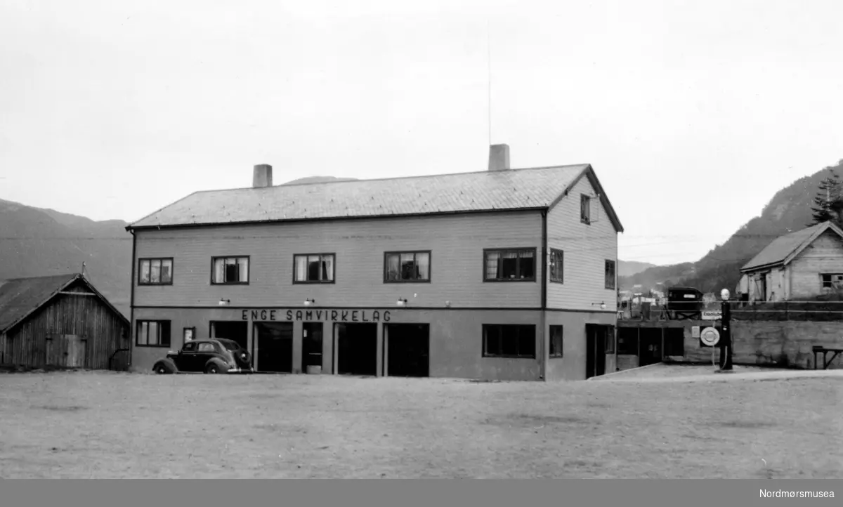 Motiv fra Enge Samvirkelag, trolig på Engjan i Halsa kommune. Like utenfor ser vi en enslig bil stående parkert. Datering er 1939. Fra Nordmøre Museums fotosamlinger. Reg: EFR
