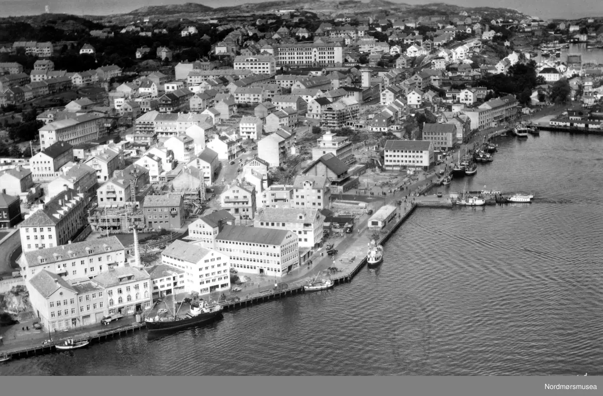 Postkort med flyfoto fra havna på Kirkelandet i Kristiansund, hvor vi ser Storkaia, Piren, Vågeveien (og Vågekaia), samt Nordmørskaia. Bildet kan trolig dateres til omkring 1952 til 1960. Fra Nordmøre museums fotosamlinger. /Reg:EFR2013/




