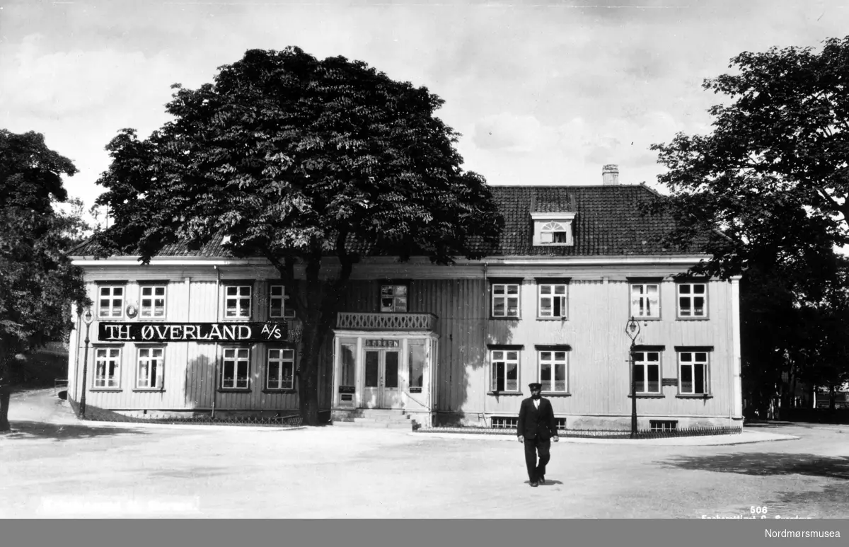 Foto av den gamle Johnsengården i Johnsenhuken på Kirkelandet i Kristiansund, som her huser blant annet Th. Øverland a/s. Datering er trolig omkring 1930 til 1939. Fra Nordmøre Museums fotosamlinger. EFR2015