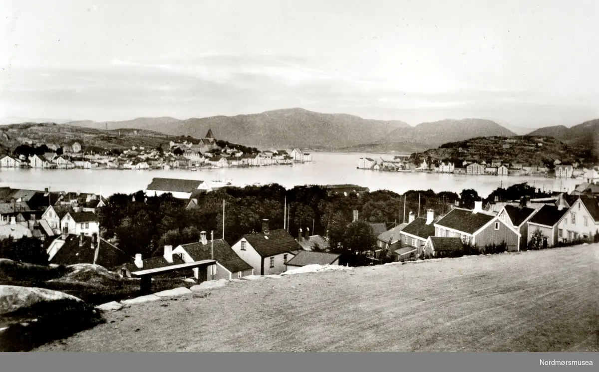 Postkort med tekst:  ";Kristiansund N."; Motivet er tatt fra L. Guttormsens gate og bebyggelsen nedenfor, havna og Nordlandet til venstre, Markussundet og Innlandet til høyre.  Bakenfor ligger Frei og Freikollen.  (Fra Nordmøre Museums fotosamlinger.) Reg: EFR
