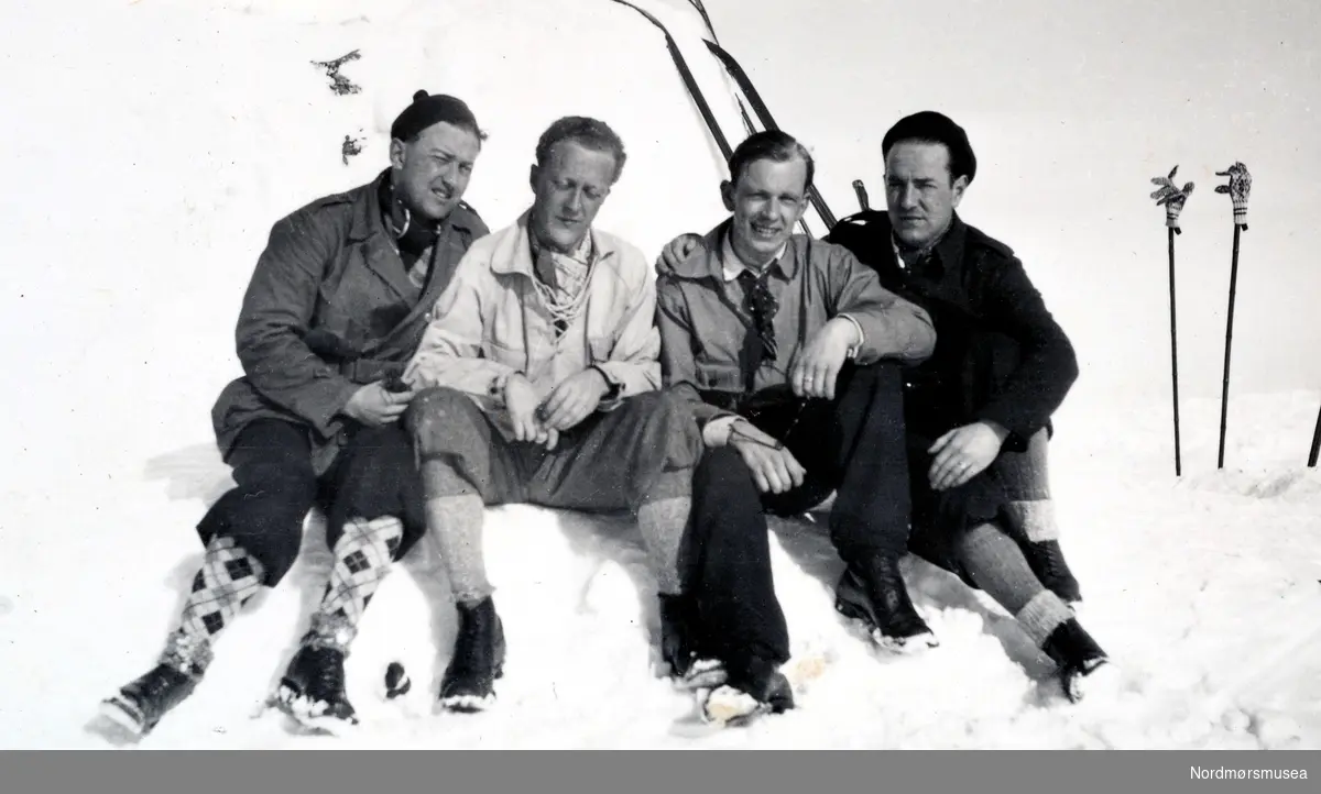 Foto av fire menn på skitur en vinterdag. Personene er trolig fra familien/slekten Heide, eventuelt fra deres bekjente. Det er ukjent hvor og når bildet er tatt, men det er trolig fra Møre og Romsdal. Bildet er hentet fra fotoalbumet til Heide og kommer i serien med reg. nr. KMb-2008-022. Fra Nordmøre museums fotosamlinger.
