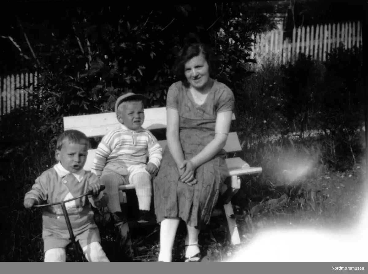 Gruppebilde, hvor vi ser Gudrun Margrete Rød, sammen med sønnene Ivar og Gunnar Rød, med Ivar på sykkelen. Bildet er trolig fotografert ved Rødfamiliens hus i Storgata 79. Ukjent datering. Fra Nordmøre Museums fotosamlinger. Reg: EFR
