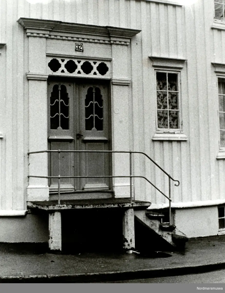 Foto fra en boligfasade med trappeoppgang ukjent hvor i Kristiansund. Legg forøvrig merke til at boligen er nummer 32 i sin gate.
 Datering er ukjent. Fra Nordmøre museums fotosamlinger.
