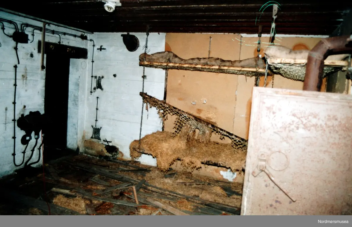 Foto fra kanonstilling i Hauggata 43 - 45 på Kirkelandet i Kristiansund. Bildet er datert 19. september 1991 og fotograf er Stein Magne Bach ved Nordmøre museum. Mannskapsrommet  i Bunker Regelbau 633 for M 19 automatisk 5 cm bombekastermaskin. Krupp fabrikat.
(Info: Bjørn Ove Angvik - 08.11.2016)   Se serie fra reg. nr. KMb-1991-039.0001 til KMb-1991-039.0017. Fra Nordmøre museums fotosamlinger.