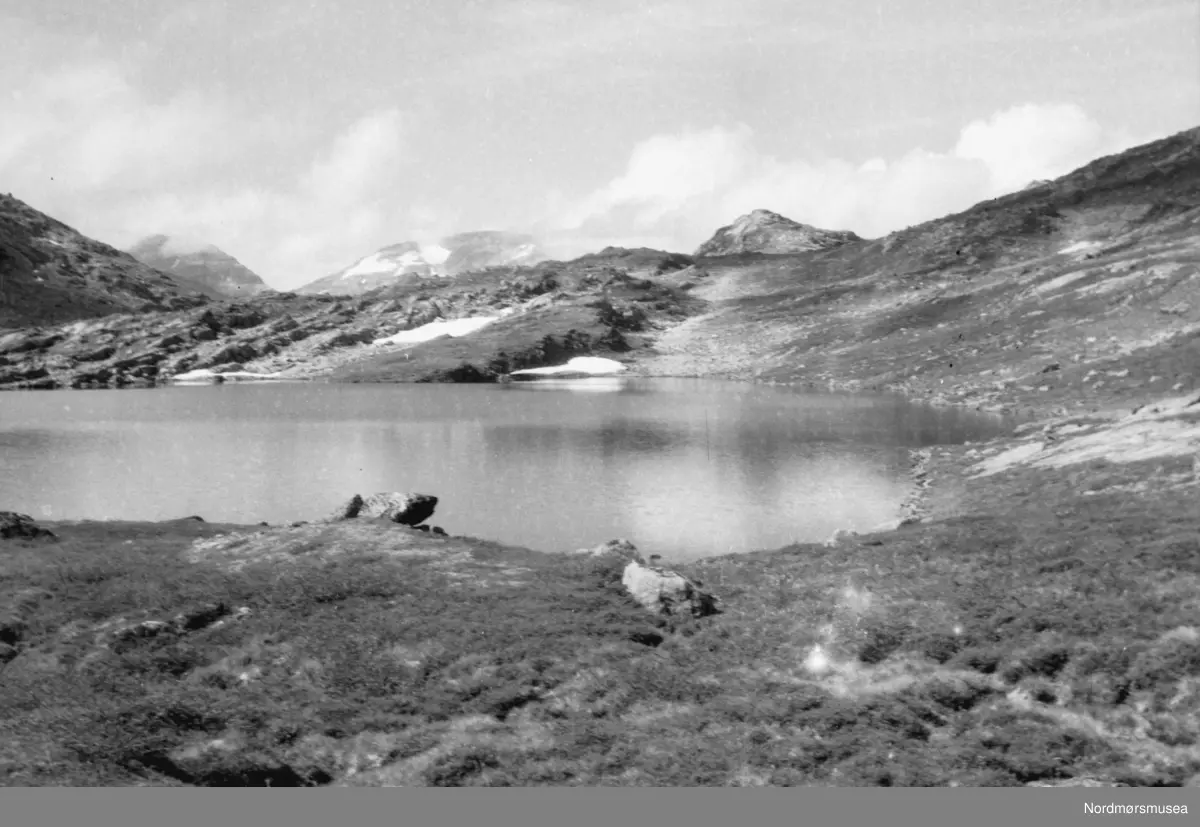 Landskapsbilde med en innsjø i forgrunnen og med de store fjell i ...