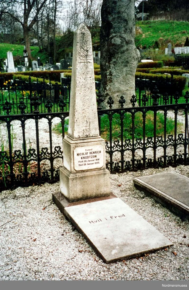 Gravsteinen til konsul Nicolay Henrich Knudtzon III. Født 26. januar 1816 - Død 28. januar 1895. merk betongplata. Knudtzons familiegravsted, Gomalandet. Se Årbok for Nordmøre museum 2000. Nordmøre museums fotosamling