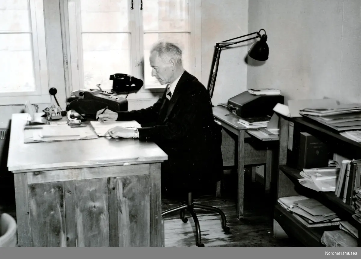Foto av kommunerevisor M. F. Glærum, her fra kommunens kontorbrakke i Roligheten, ca 1948/1949. Fra Nordmøre museums fotosamlinger.
