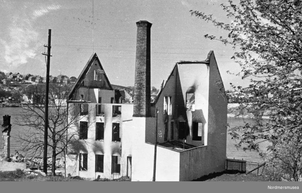 Bak på fotoet er notert Offenberg Co AS. Dette er Offenbergs eiendom på Nordlandet som ble flammenes rov under tyskernes bombing av Kristiansund i aprildagene 1940. Oljeklær ble produsert her. Fabrikken ble gjenreist og produksjonen ble videreført etter krigen. I bakgrunnen ser vi øvre bydel med Moskvahaugen på Kirkelandet til venstre og Nordsundet og Gomalandet til høyre.

Informant Johan Tømmervåg: 
Dette er en fabrikkbygning som i 1940 huset Offenbergs fabrikk.
 Firmaet kjøpte denne av Møre Margarinfabrikk.
 Det er Gomalandet vi ser i bakgrunnen.


 Familien Offenberg hadde drevet en fabrikk som fremstilte arbeidsklær i akkurat fire år da krigen kom. Den var egentilig en videreføring av Kristiansunds Oljeklædefabrik, som var drevet av P.A. Offenbergs far, Chr. Offenberg. Firmaet var raskt ute og fikk byggetillatelse for å bygge en ny fabrikk i 1941. Den sto ferdig til bruk året etter. Den ble velkjent for å produsere arbeidsklær og
Brakar var navnet på produktetene.
 Dongeriklær og arbeidsskjorter var det som ble markedsført, og de fikk ord på seg å være av meget god kvalitet.
 Tidligere hadde familien drevet Kristiansunds Oljeklædefabrikk.
 Fabrikken disponerte en gulvflate på cirka 600 kvadratmeter og hadde 25 ansatte.
 Det lyktes eierne å få bygge en ny fabrikk under krigen, og den sto ferdig i 1942.
 Kilde:
 En bok om Kristiansunds næringsliv 1742-1942.
