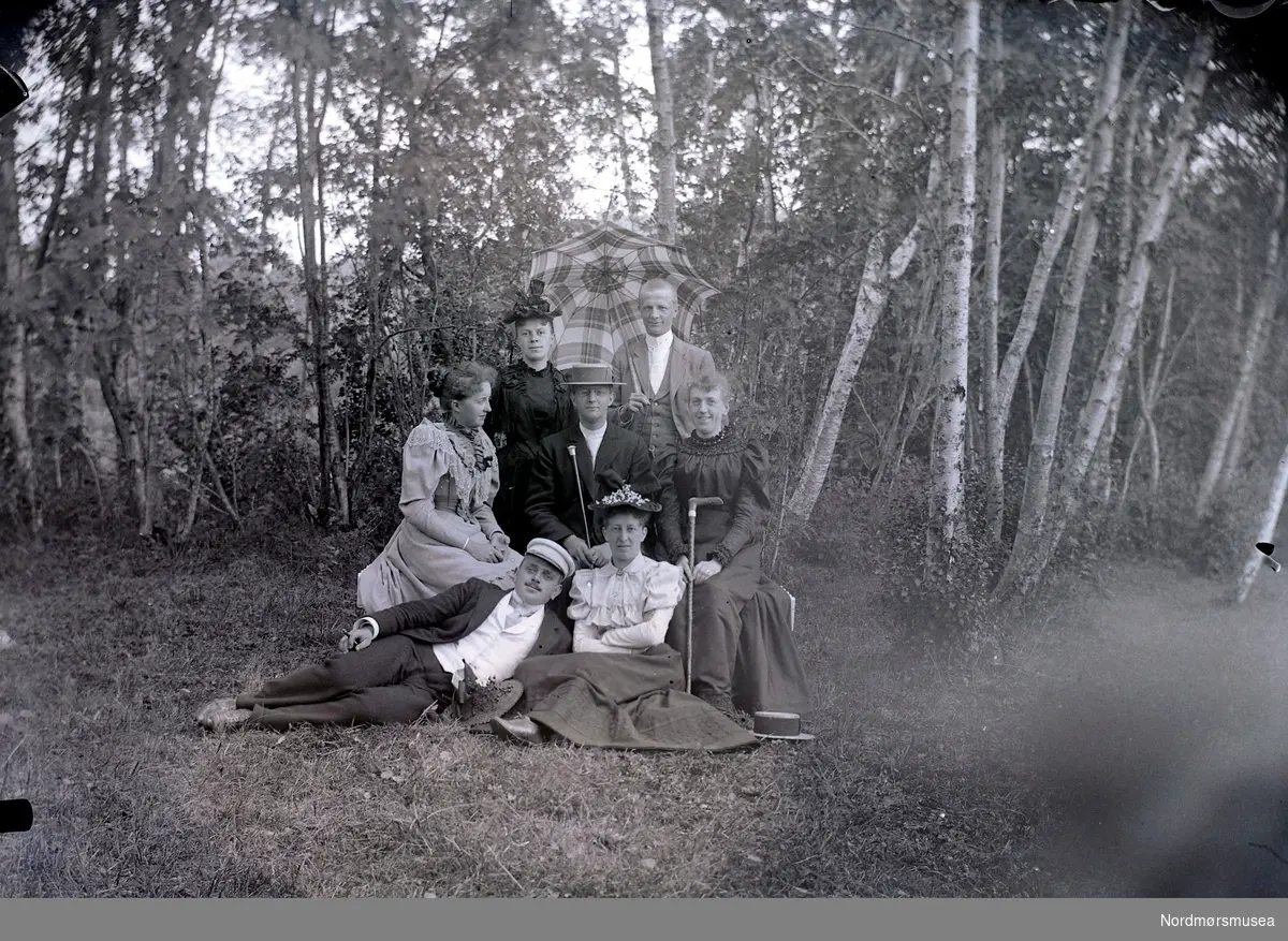 Foto fra Retiro i Molde? Alle kvinnene på bildet er muligens fra Johnsenfamilen. Det er mulig Birgitte Hilmara Johnsen vi ser i sort ved siden av mannen med paraply på bakre rekke.  Johanne Hanken Johnsen sitter lengst til høyre i midterste rekke. Fra Nordmøre museums fotosamlinger. Reg: EFR
