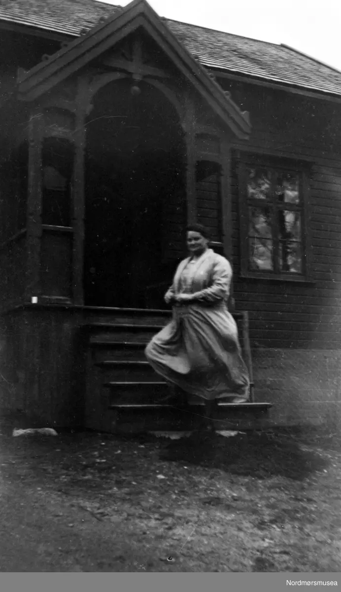 ferm dame på trappa foran trehus (Fra Nordmøre Museums fotosamlinger)
