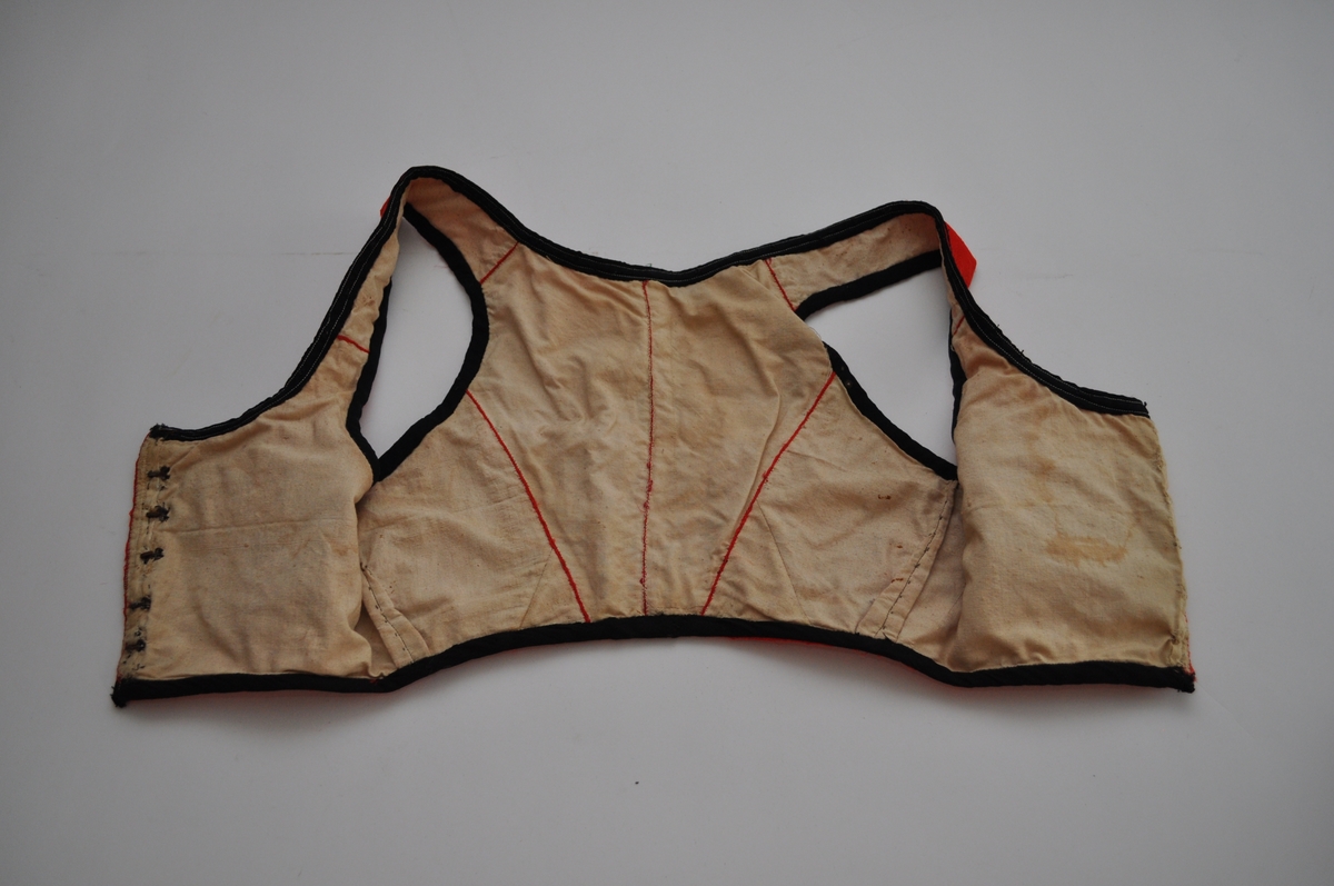 Livet er sannsynligvis et bunadliv til nasjonaldrakt. Det er sydd av et rødt, mønstervevd stoff med avanserte vevbindinger i kombinasjon. Mønsteret er dels valknuter, firkantmotiver og dels frie blomstermotiver. Livet lukkes foran med hekter og har hatt maljer. Det er kantet med svarte fløyelsband. Fôret er av ubleiket bomullslerret. Plagget består av to framstykker og to bakstykker samt seler som er sydd fast til for- og bakstykker. Framstykkene går fra midt foran til langt tilbaketrukne sidesømmer, men har et legg under hvert ermehull. Delene er sydd sammen med spilesøm med svært små sting. Kantebanda er sydd på med maskin.