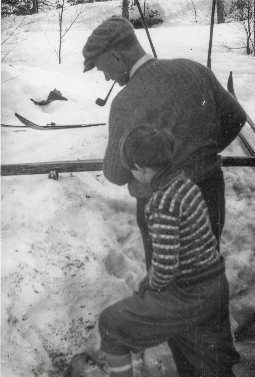 Frans W. Bruce med pipe smører ski medan dotter ser på.