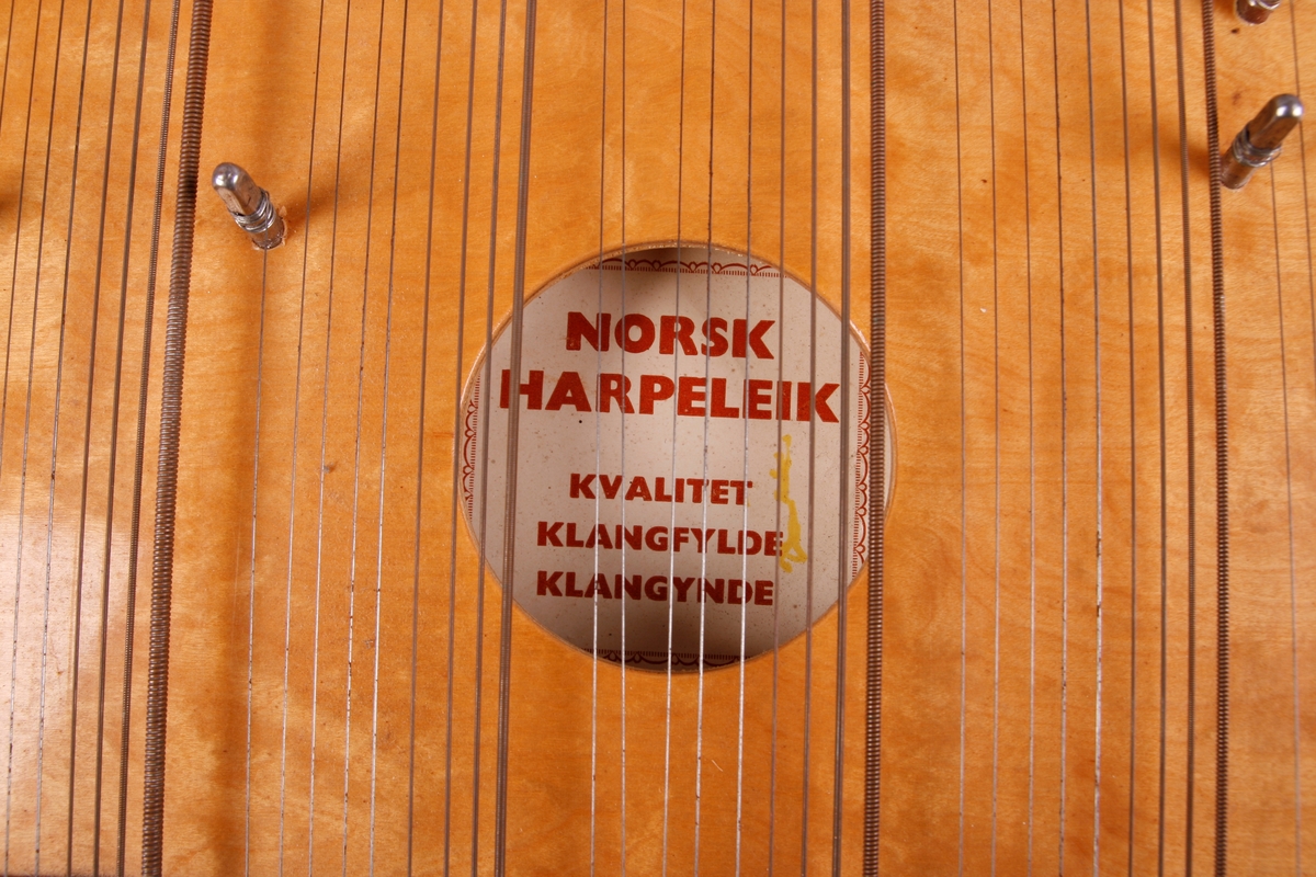 Rektangulær korpus med lokk og bunn i lysebrunt tre. Sargen er mørkt tre. Bunnen er flat. Nedre sarg er flat, og de andre tre sidene er buet. Instrmentet har en "arm" på venstre side. Fra denne armen går et håndtak i form av en søyle. Tre metallknapper på venstre side nedenfor håndtaket. Ved disse er det to metallskruer/ringer her som lager hull inn i resonanskassen. 

64 strenger som er gruppert i sju akkorder. Fra venstre: F-dur, C-dur, G-dur, D-dur, A-dur, E-dur, H-dur. Nederst på instrumentet er det påmontert et brett som beskytter strengefestet. Under strengene går det for hver akkord en stang som kan bøyes oppover. Med disse kan man forandre tersen i hver akkord, og dermed spille i moll. 

Nederst, før strengefestet og brettet er det skrudd på en metallplate som beskriver tonehøyder via notelinjer, samt notenavn. Etikett på kremhvitt (falmet?) papir er pålimt inne i kassen.