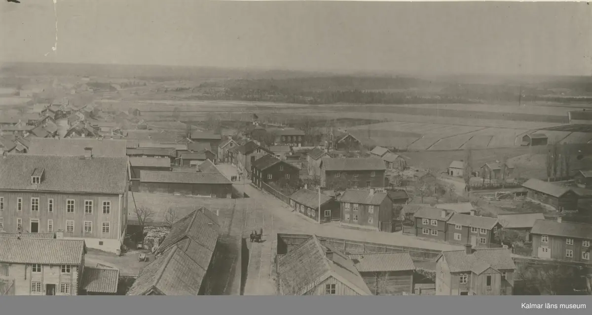 Vy över Vimmerby stad. Detta är ett foto på den gamla bebyggelsen vid torget i Vimmerby. Kortet är taget innan 1866 då man började bygga stadshotellet på tomten där den låga, breda stugan ligger mitt i bild.