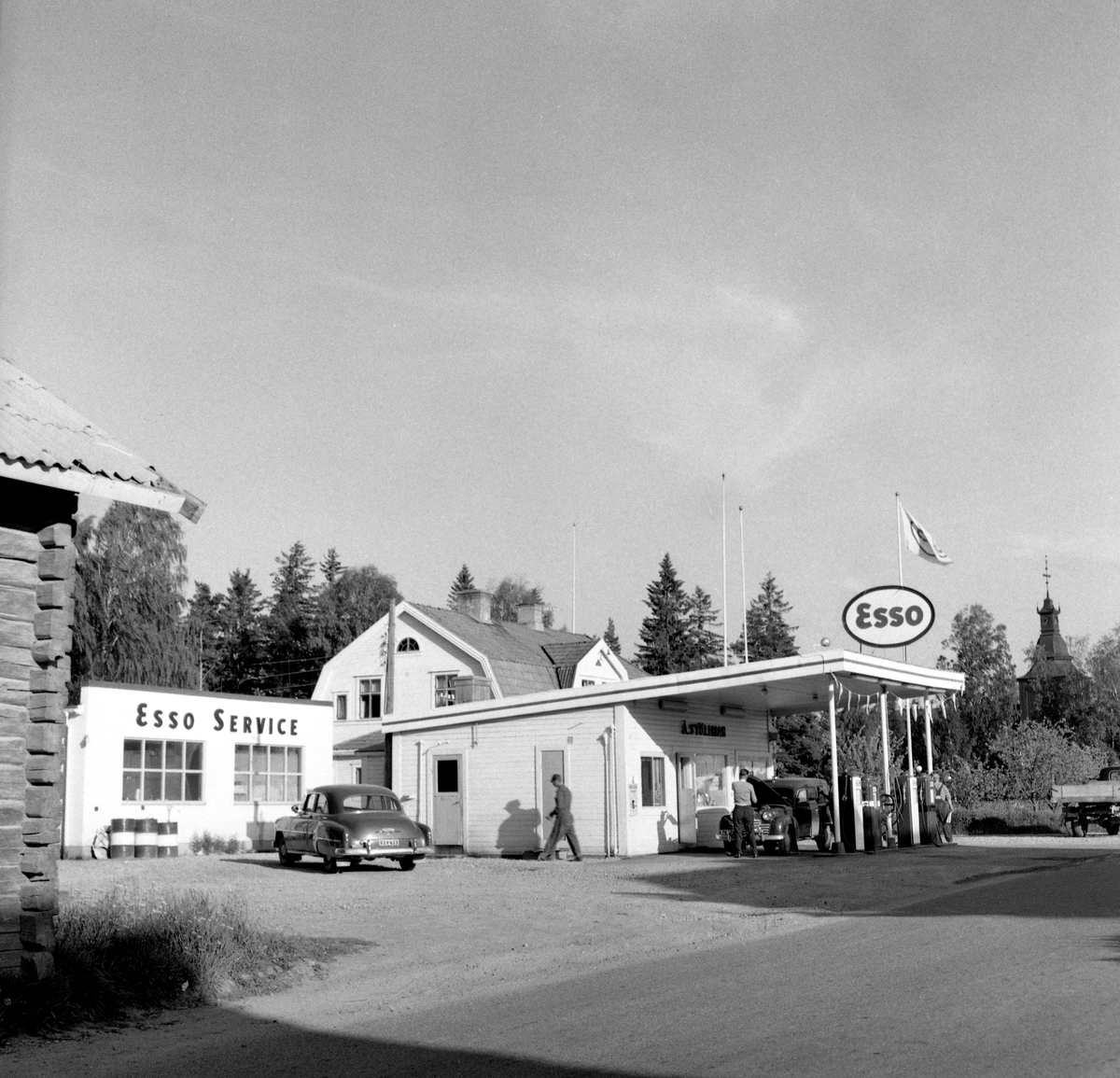 Någonstans i Värmland - från slutet av 1950-talet. Kommentar från användare: "Det är Esso i Ekshärad med kyrkan i bakgrunden. Fotot taget från nordväst".