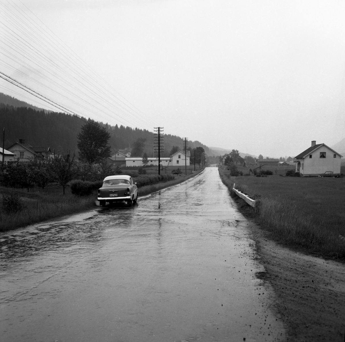 Någonstans i Värmland - från slutet av 1950-talet: Sysslebäck. Lämna gärna en kommentar om du vet något om bilden.

Kommentar från användare: "Bilden torde vara tagen söderut från södra Sysslebäck (Hole), strax söder om infarten till nuvarande Sysslebäcksbadet. Till höger i bakgrunden syns Branäsberget."