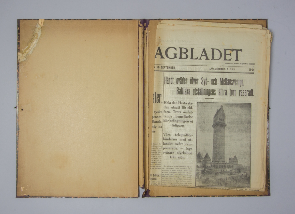 Portfölj av marmorerad papp. Sammanhållen med knytband. Rygg av lila linne. Innehåller enbart flera exemplar av Svenska Dagbladet från 1914.